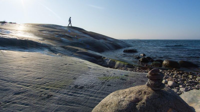 Poika kävelee Itämeren kallioilla.