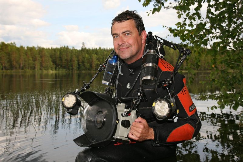 Valokuvaaja Pekka Tuuri seisoo vedessä sukellus- ja valokuvausvarusteissa