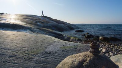 Poika kävelee kalliolla meren rannalla
