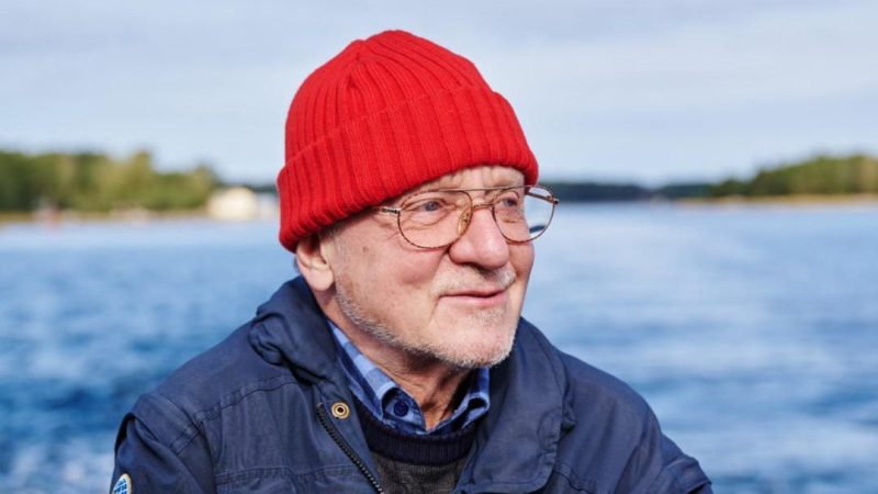 Juha Nurminen veneessä punaisessa pipossa.