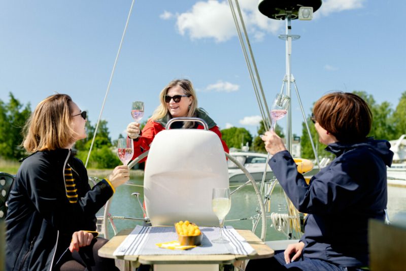 Three persons in a sailing boat raising a glass