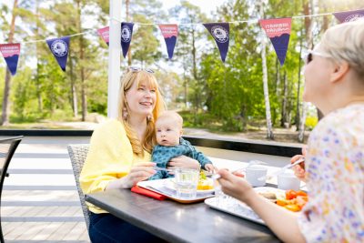 Nainen ja lapsi syömässä Itämeripäivän lounasta ulkona terassilla