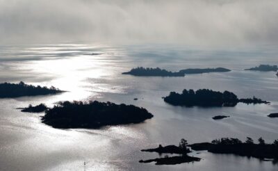 Ilmakuva Saaristomerestä vastavaloon. Saaret näyttävät mustilta tyyntä vedenpintaa vasten