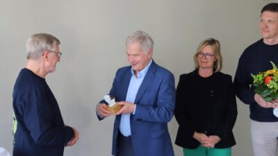 Presidentti Niinistölle ojennetaan palkinto. Kolme henkilöä seisoo Niinistön ympärillä.