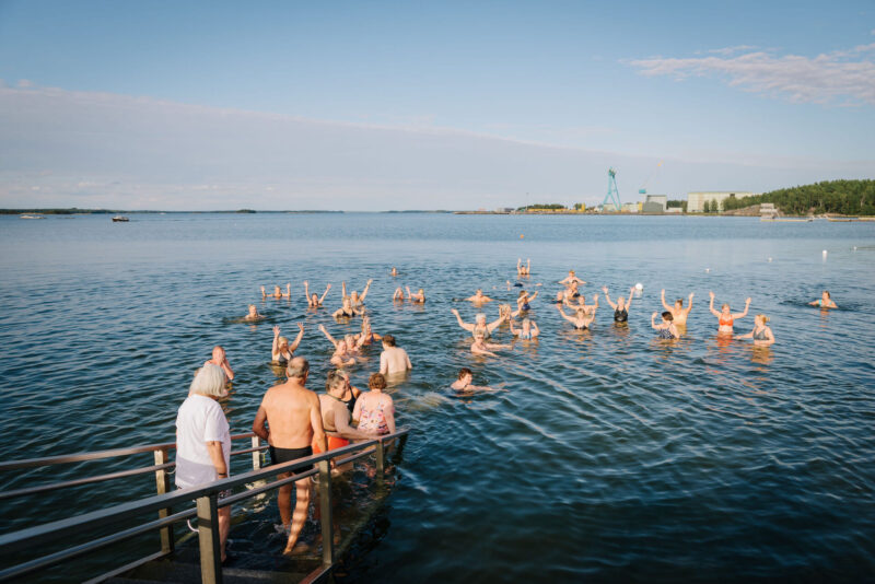 Ihmisiä menossa uimaan laiturilta.